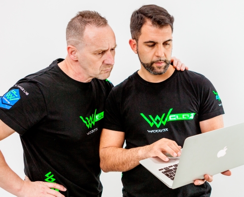 Zwei Männer stehen mit Trainingsoutfit vor einem Laptop